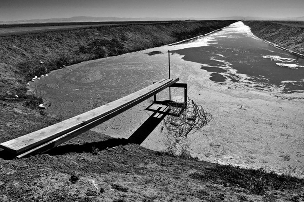 Under an unrelenting summer sun, miles of irrigation canals stretch out over the Central Valley bringing the water of the Kings to thousands of acres.